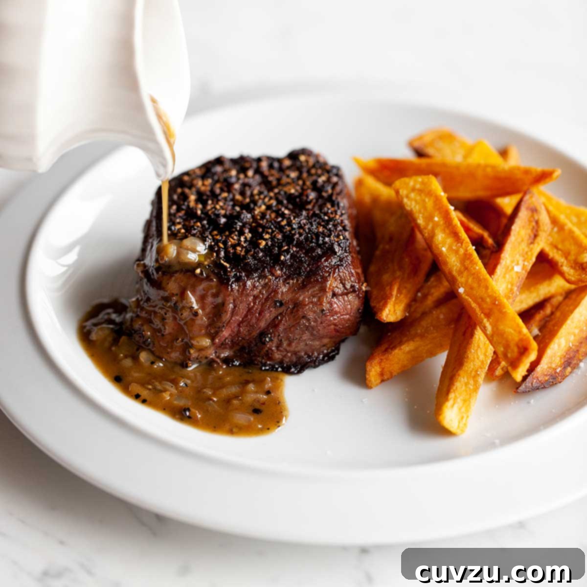 Julia Child Cooks Up a Series for HBO Max 7 A person drizzling sauce over a steak au poivre on a white plate with sweet potato fries.