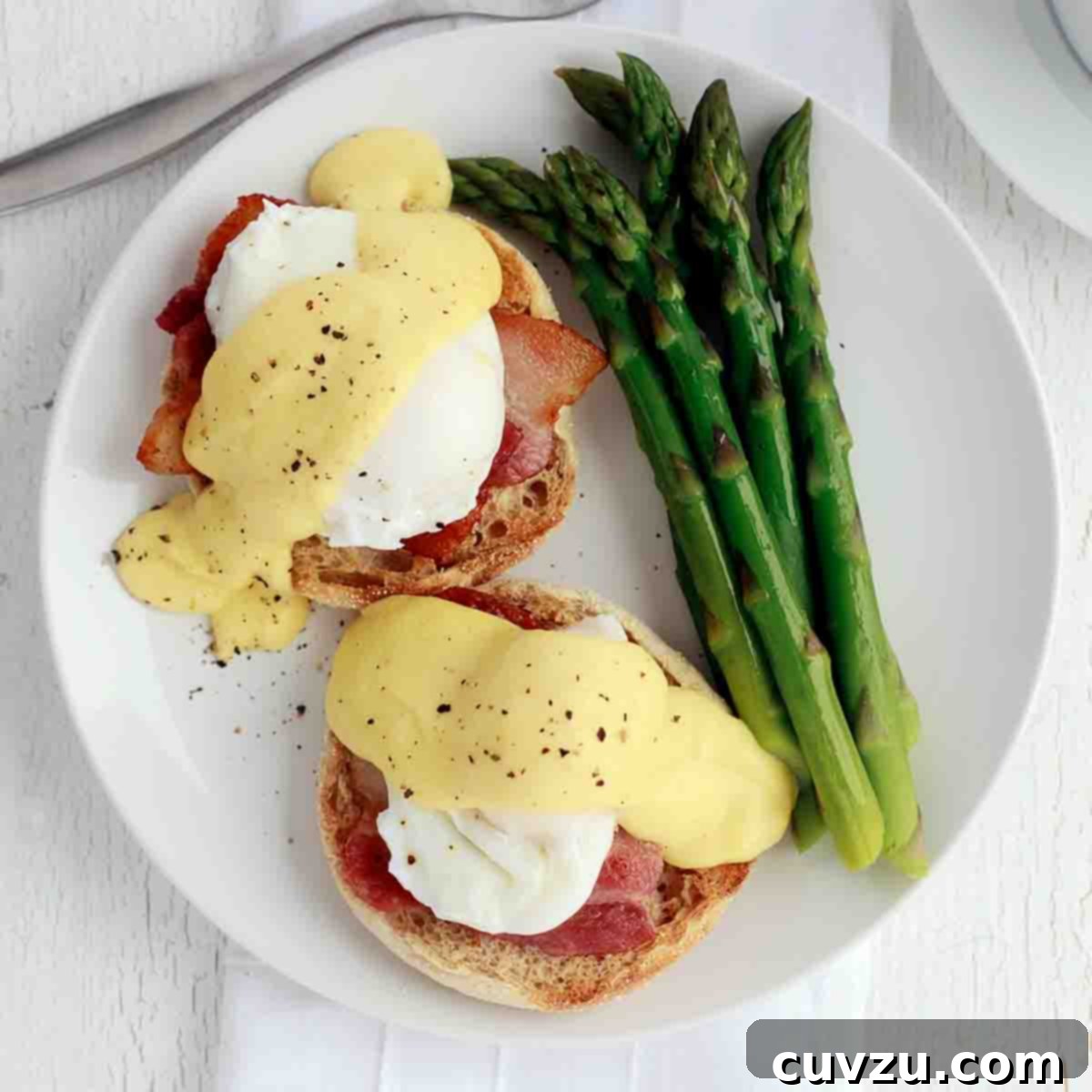 Julia Child Cooks Up a Series for HBO Max 8 Two Julia Child's eggs Benedict on a white plate with a side of asparagus.