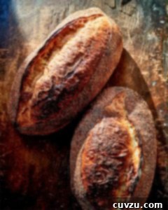 Two oval loaves of filone on a wooden board.
