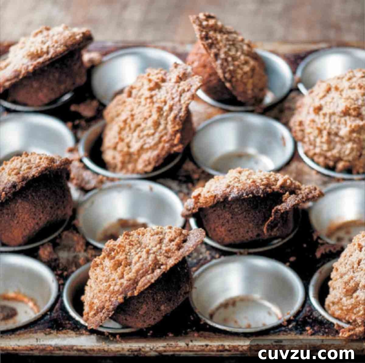 A muffin tin half filled with baked carrot muffins, showcasing their golden-brown tops and moist texture.