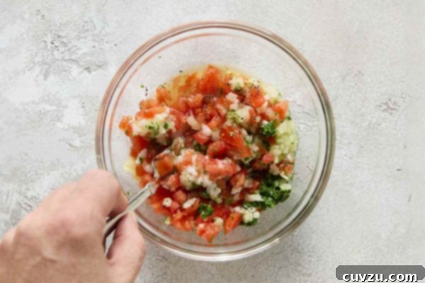Flame-Kissed Skirt Steak with Vibrant Salsa 11 A person mixing salsa ingredients in a small bowl.