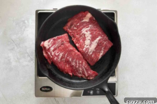 Flame-Kissed Skirt Steak with Vibrant Salsa 13 Two pieces of skirt steak in a cast iron pan.
