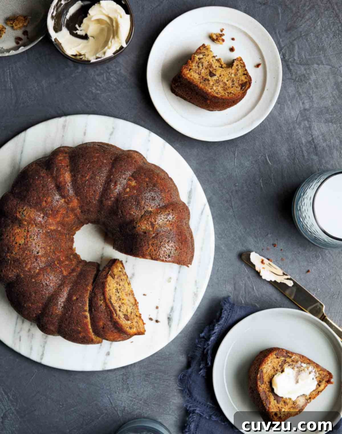 A Bundt banana bread on a white serving platter and individual slices on two plates.