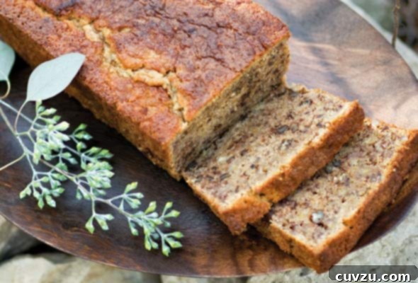 A partially sliced loaf of gluten-free banana bread on a wooden platter.