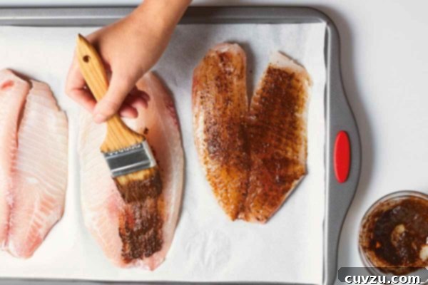 Zesty Chile-Lime Tilapia Bake 3 A person making baked tilapia with chile and lime by brushing tilapia fillets with a spice mixture.