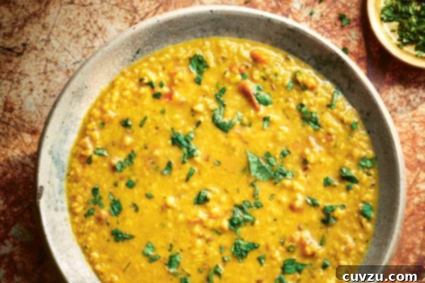 A ceramic bowl filled with tarka dal and sprinkled with cilantro with a small bowl of chopped cilantro on the side.
