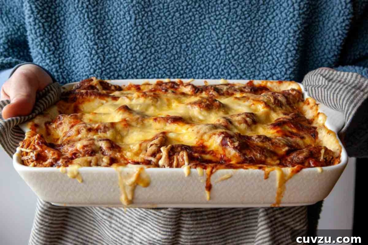 A person gently holding a finished Croque Monsieur casserole, showcasing its golden-brown top and inviting texture, ready to be served.
