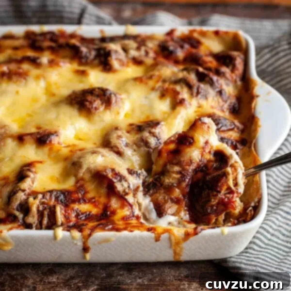A finished Croque Monsieur casserole, golden and bubbly, with a serving spoon nestled in its creamy layers, presented in a white baking dish.