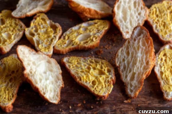 Halved croissants, delicately spread with Dijon mustard, awaiting the savory fillings for the Croque Monsieur casserole.