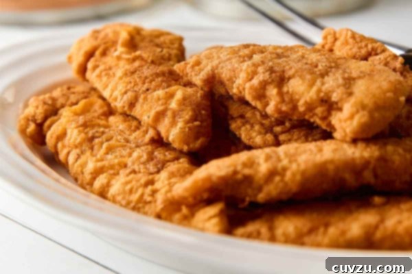 Golden Skillet Chicken Bites 19 A white oval platter of pan-fried chicken tenders.