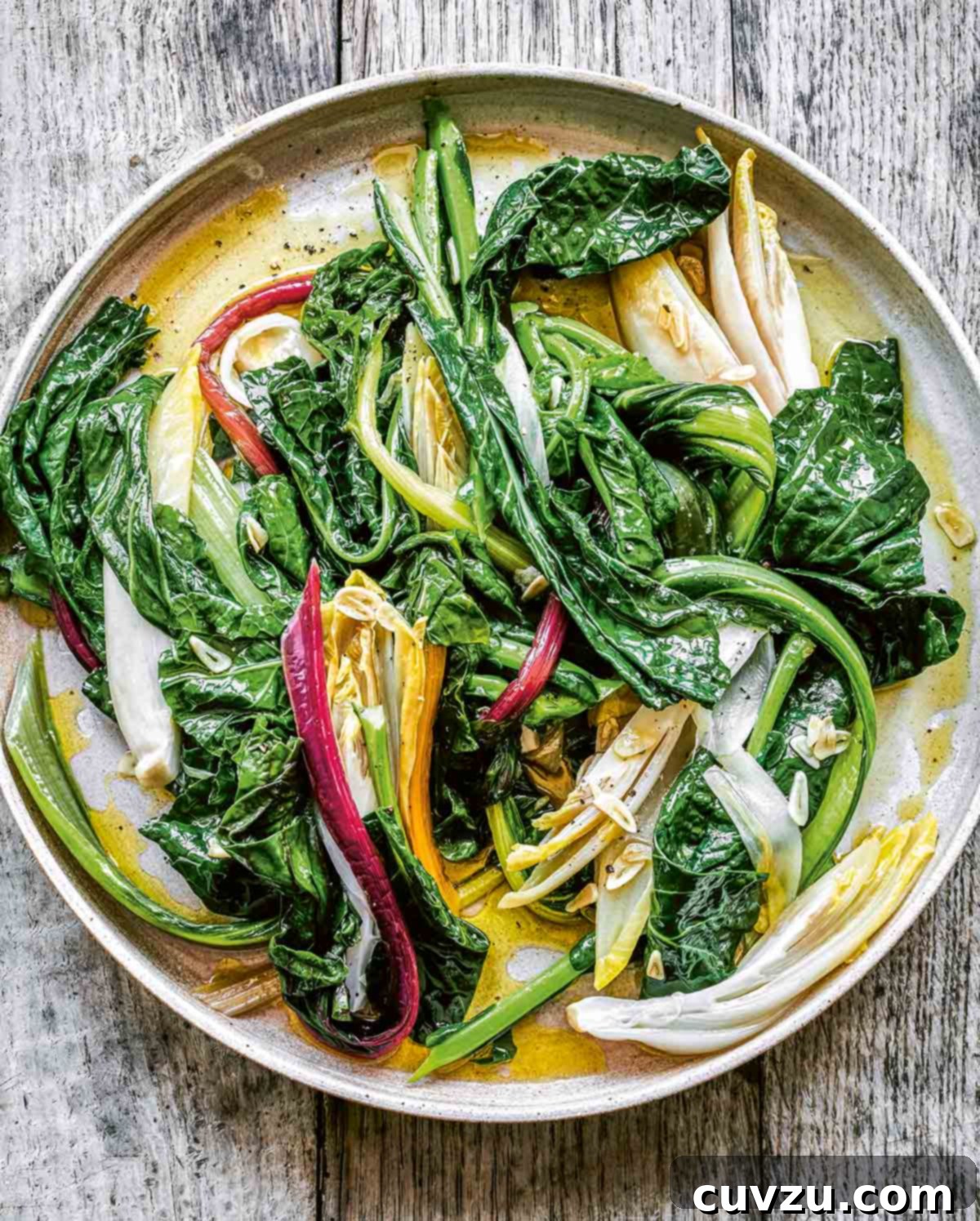 A simple white plate generously filled with bright green horta, or boiled greens with visible flecks of garlic.