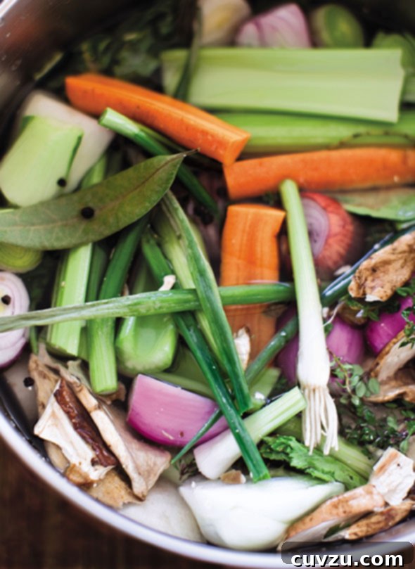 The ingredients for vegetable broth, including carrots, celery, bay leaves, and onions, in an enamel pot.