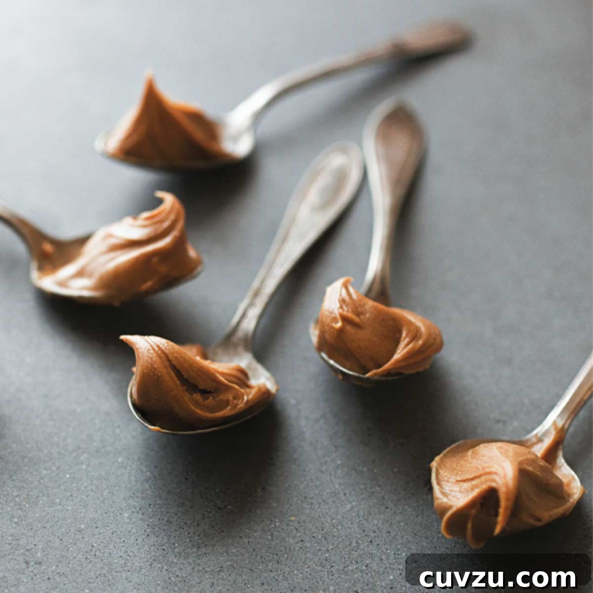 Five teaspoons, each topped with a swirl of homemade peanut butter.