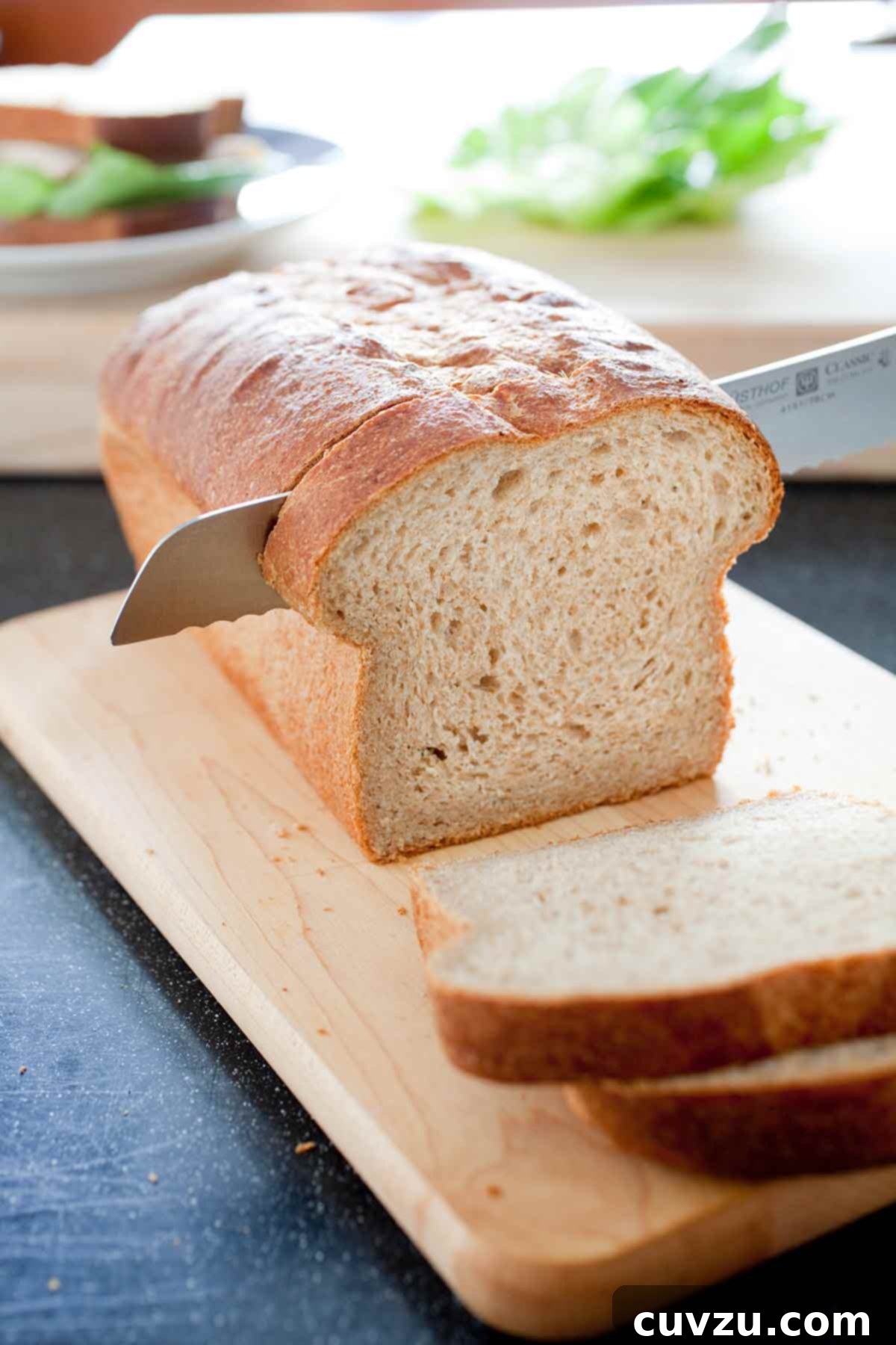 Homemade Whole-Wheat Sandwich Bread 2 A partially sliced loaf of whole-wheat sandwich bread on a wooden cutting board, showcasing its tender crumb and golden crust.