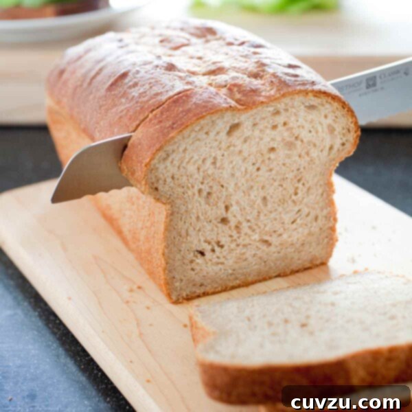 A partially sliced loaf of whole-wheat sandwich bread on a wooden cutting board.