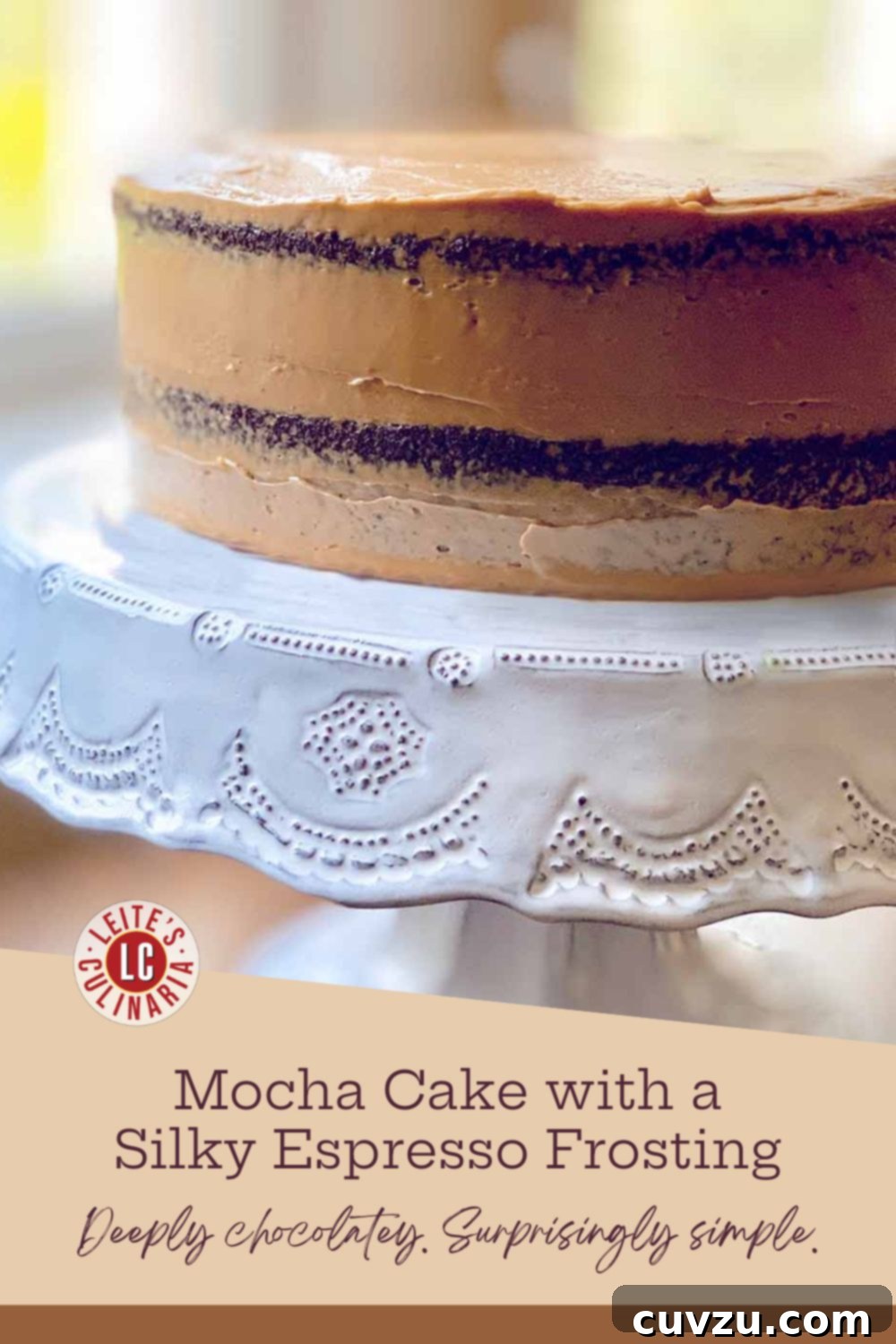 Velvet Mocha Delight 3 A sour cream mocha cake with espresso frosting on a decorative white cake stand, against a blurred window background, ready to be enjoyed.