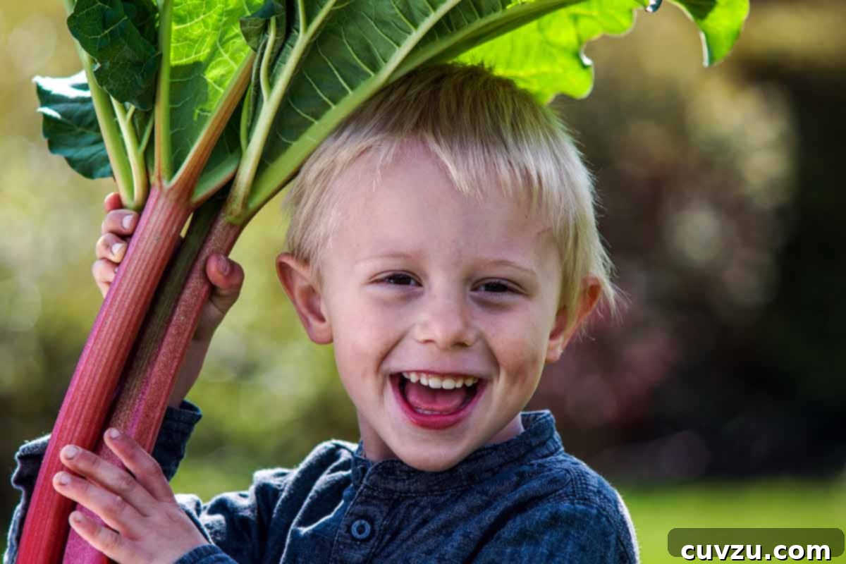 Rhubarb Savvy: Pick It, Keep It, Freeze It 3 A smiling child holding large stalks of rhubarb, emphasizing its impressive size.