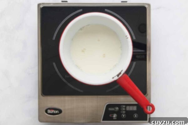 A pot with milk on a burner.
