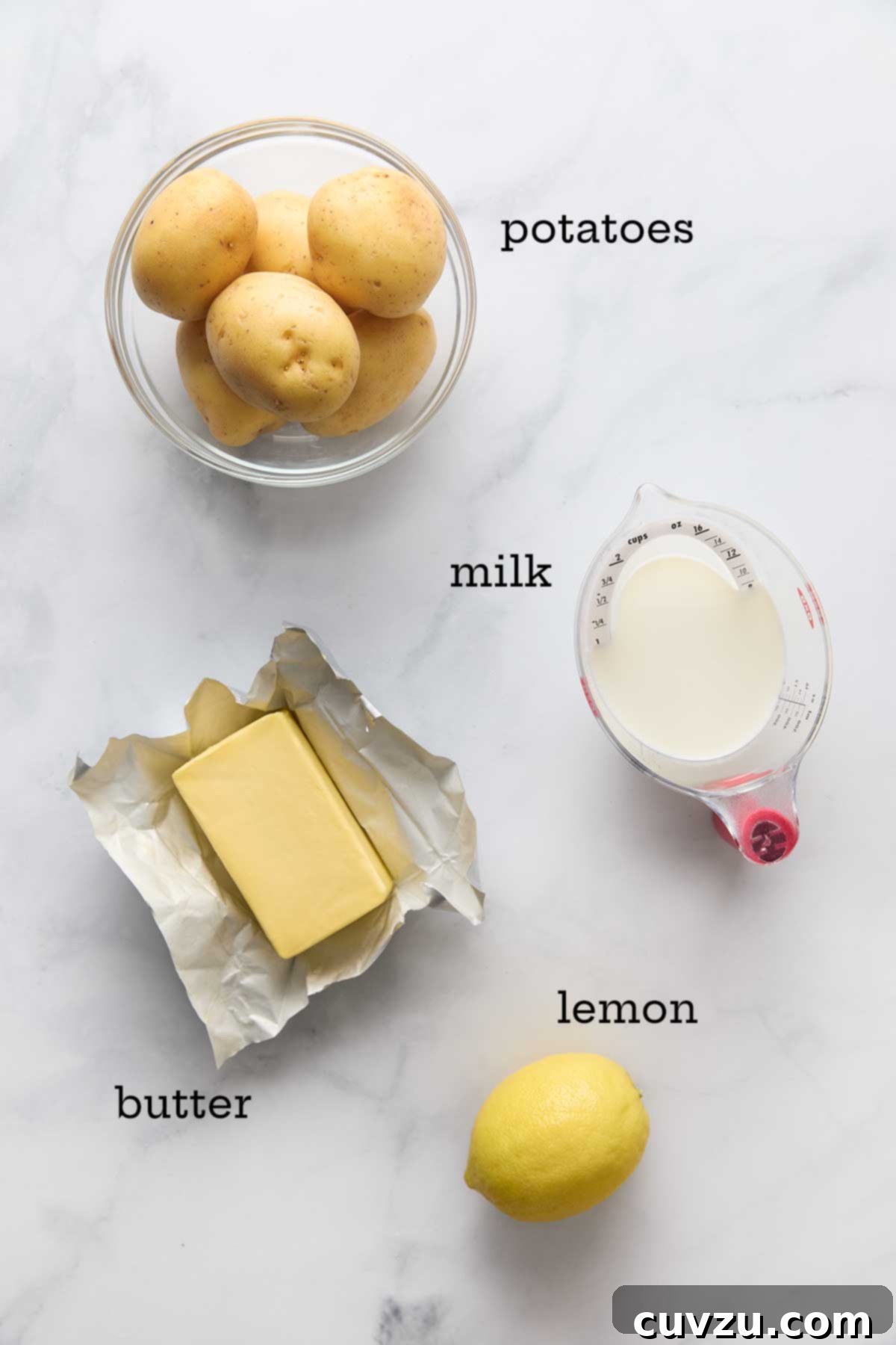 Ina Gartens Bright Lemony Mashed Potatoes 5 A carefully arranged display of key ingredients for lemon mashed potatoes: vibrant yellow lemons, golden Yukon Gold potatoes, creamy butter, and fresh milk.