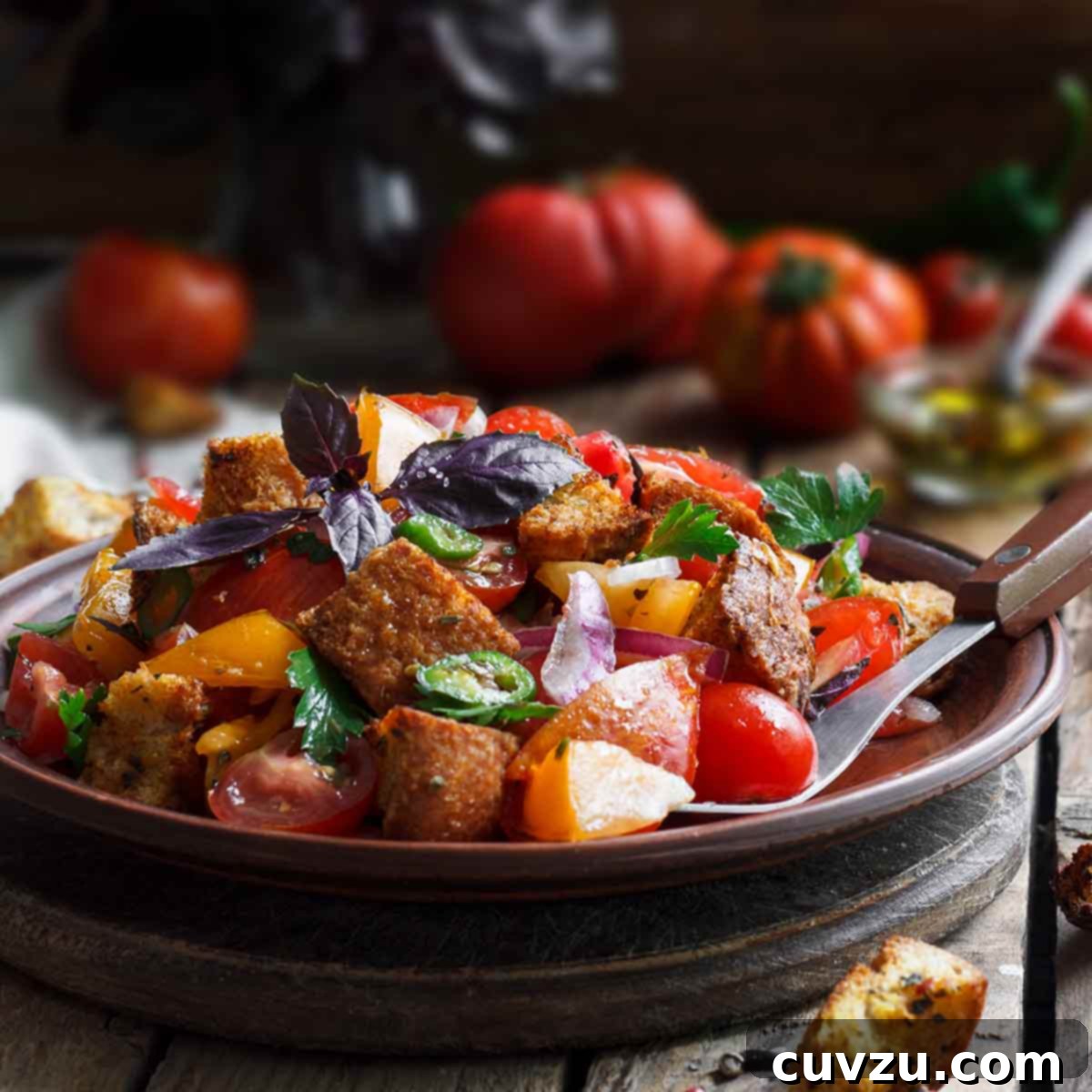 Wood bowl of panzanella from Ina Garten with bread chunks, tomatoes, peppers, cucumbers, basil, and parsley, a refreshing summer salad.