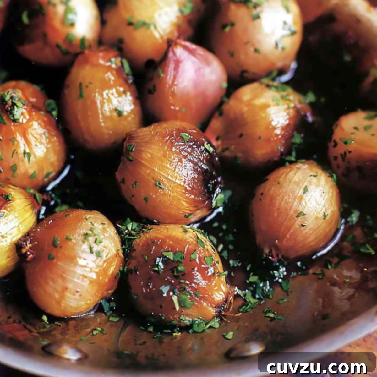 A skillet full of Ina Garten's caramelized shallots, garnished with parsley, a versatile side dish.