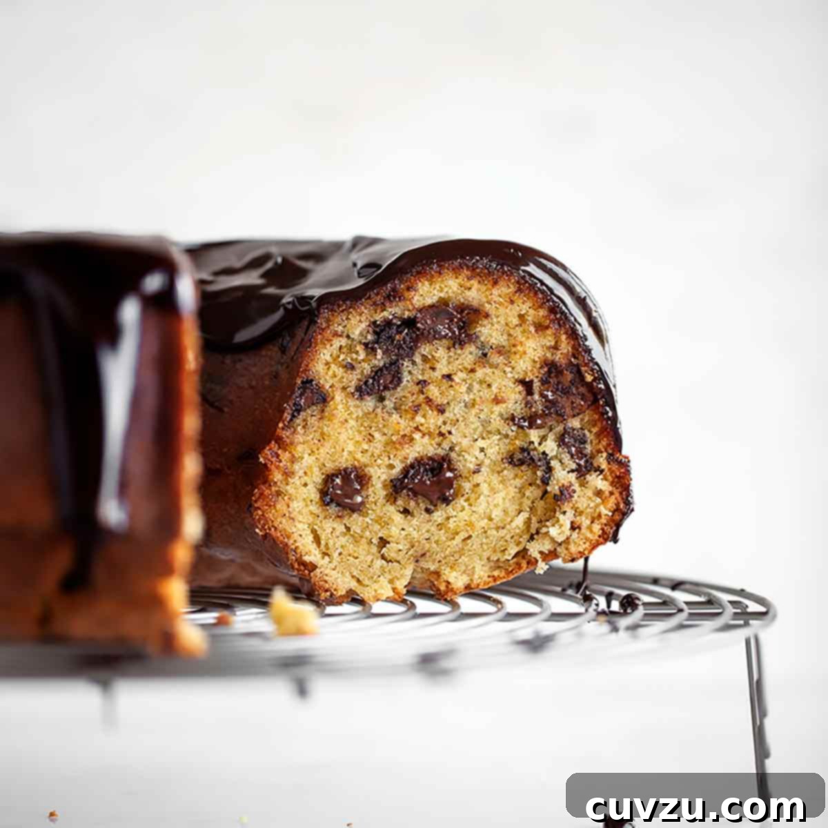 A partially cut orange chocolate chunk cake on a round wire rack, a delightful Ina Garten dessert.