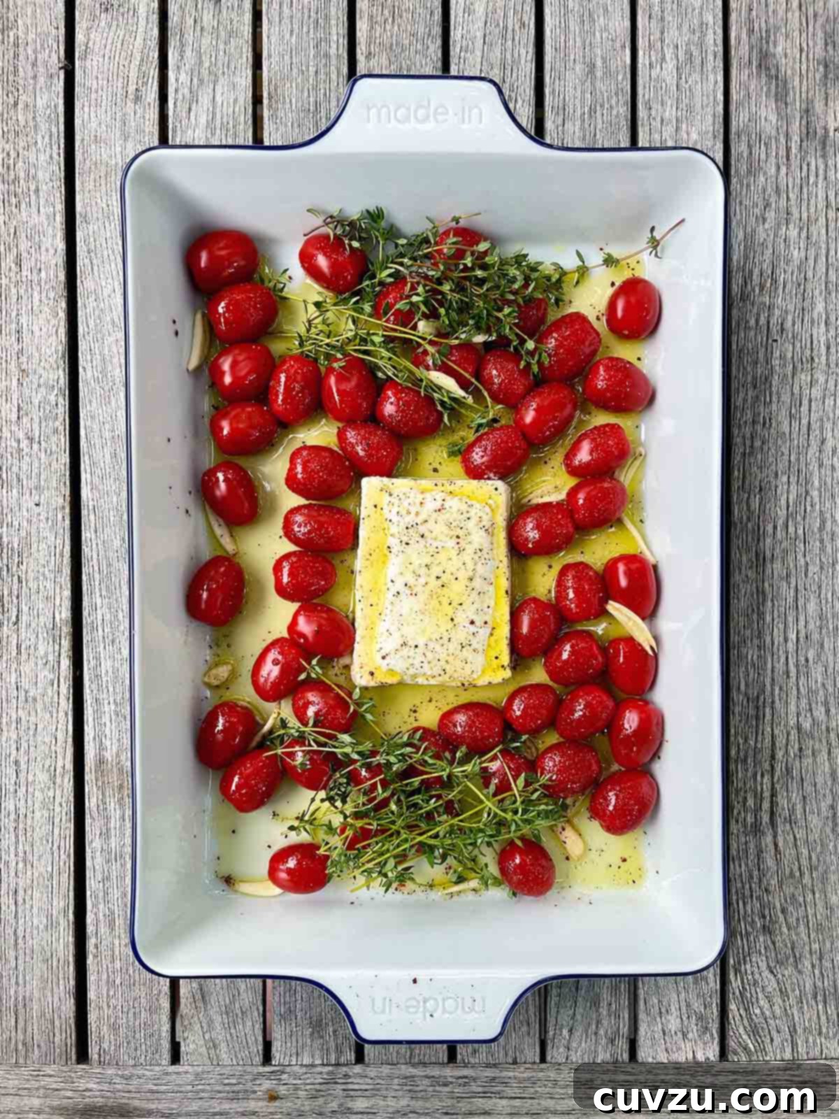 Creamy Feta and Shrimp Pasta Bake 3 Fresh ingredients laid out for baked feta pasta prep, including cherry tomatoes, garlic, feta block, and fresh thyme.