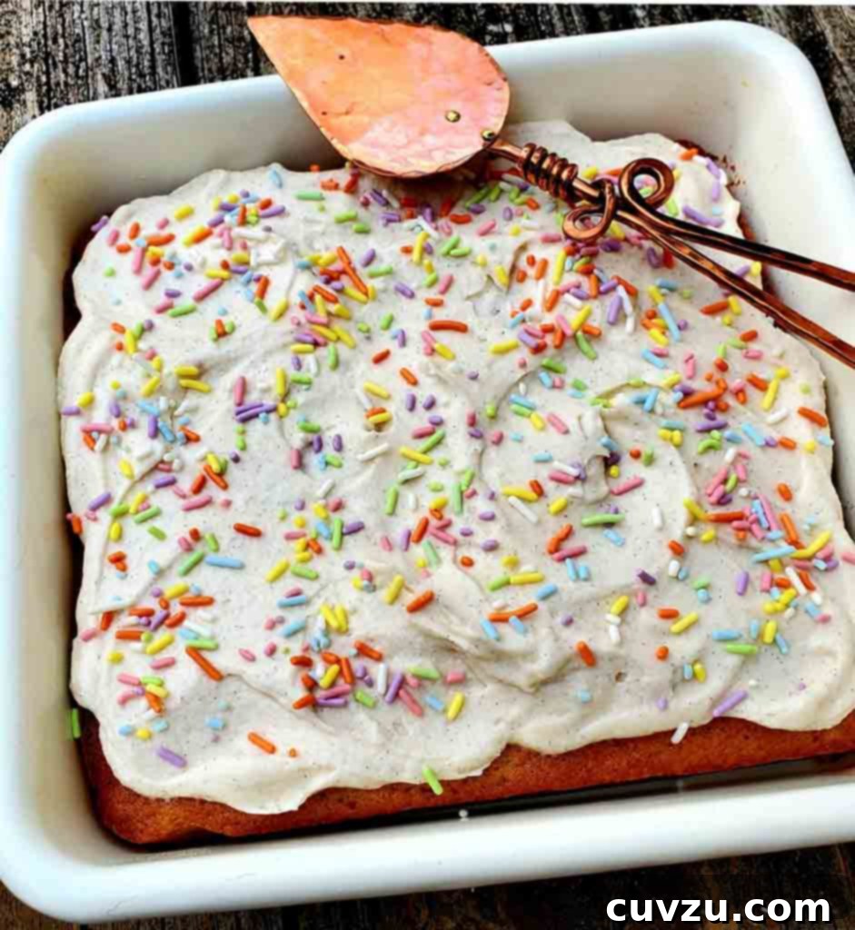 Buttermilk Vanilla Bliss 5 A square vanilla buttermilk cake in a white baking dish, frosted and decorated with sprinkles.
