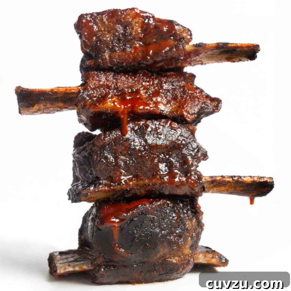Four grilled short ribs in a stack on a white background.