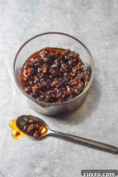 A glass bowl partially filled with Thai chili jam and a spoon on the side, highlighting its rich texture and color.