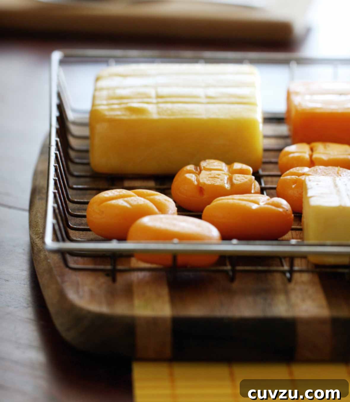 Elevate Your BBQ: 14 Must-Try Smoker Recipes 11 A wire basket on a wood cutting board containing several types of cheese, including smoked cheddar cheese.