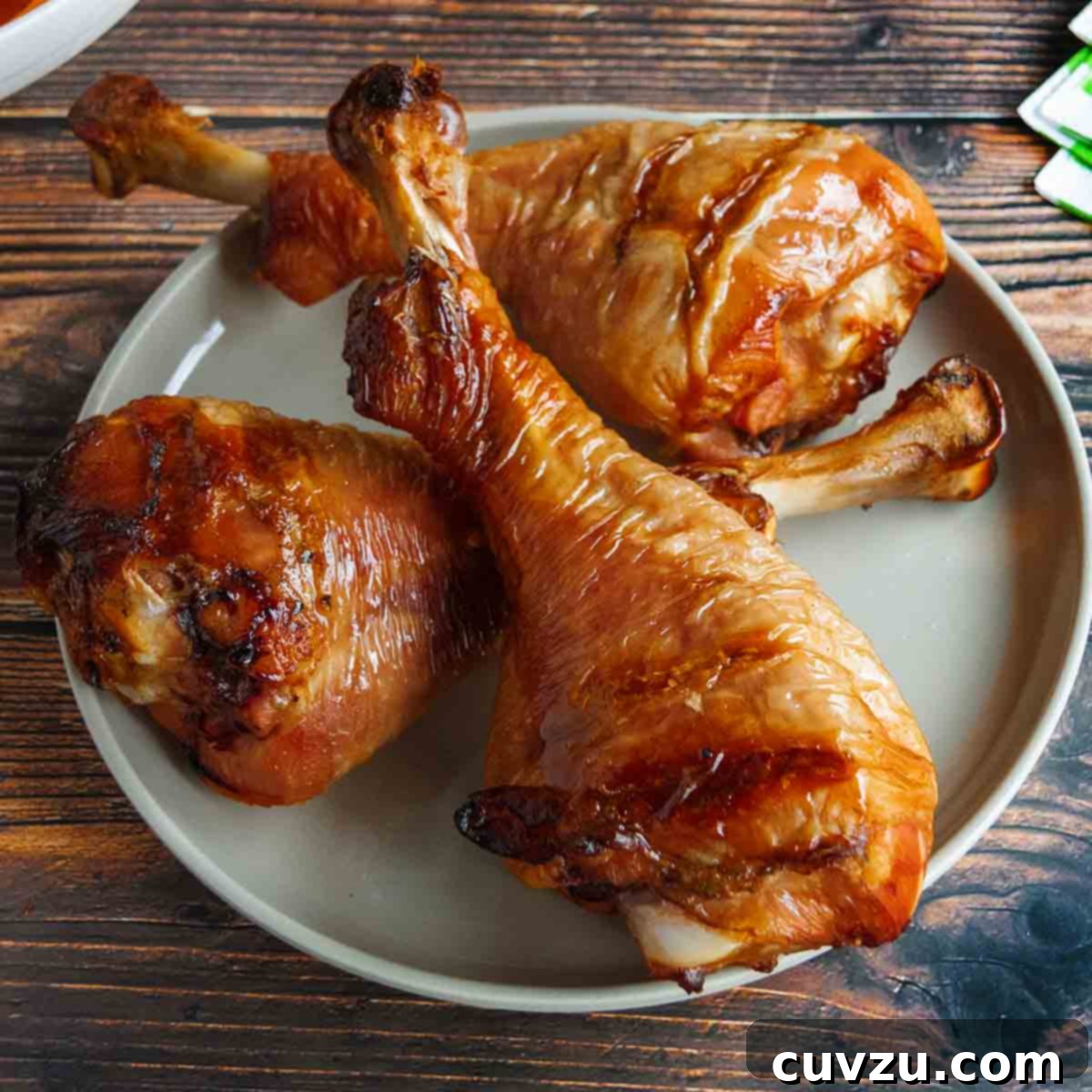 Elevate Your BBQ: 14 Must-Try Smoker Recipes 6 Three smoked turkey legs on a plate with a bowl of coleslaw in the background.