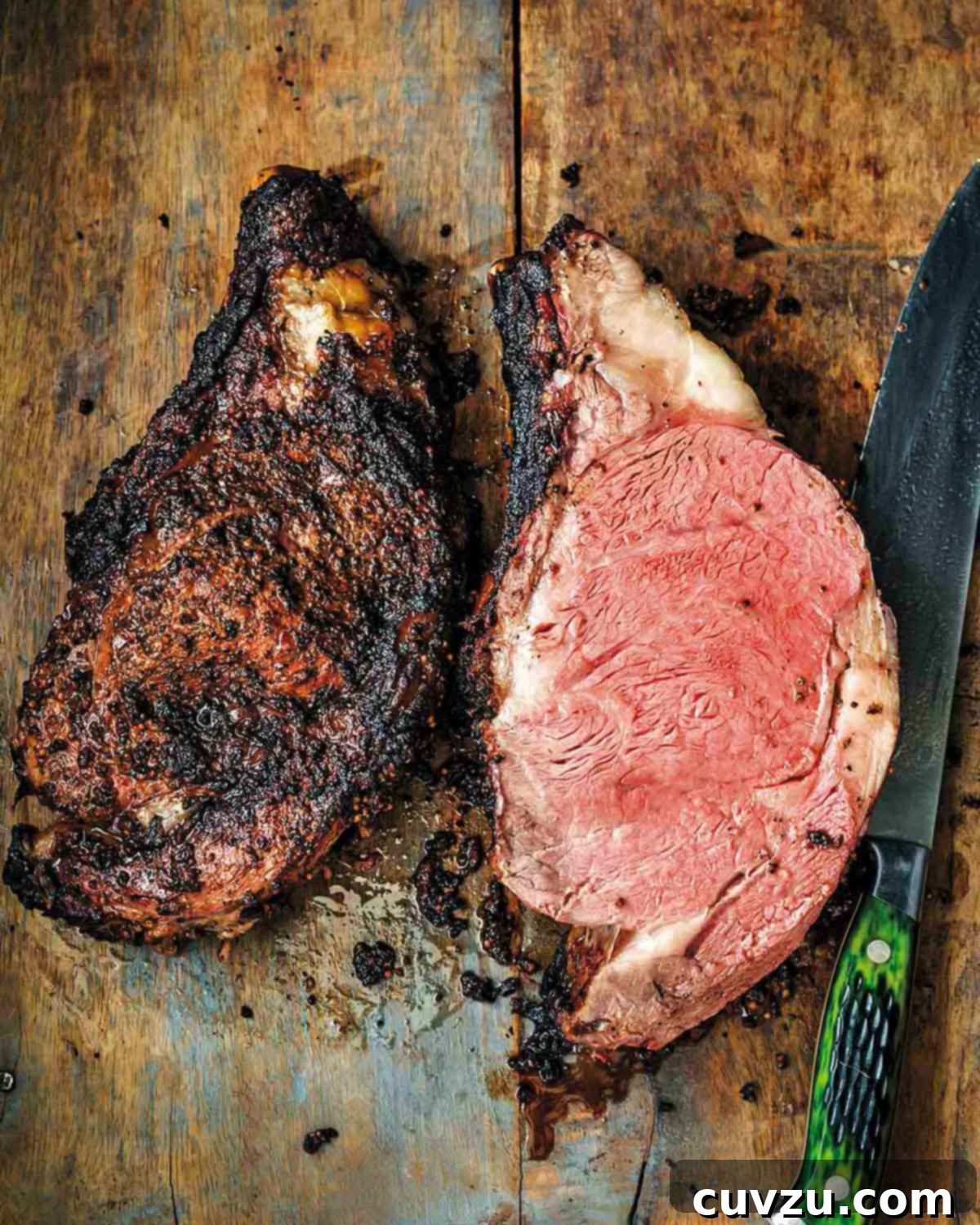 Elevate Your BBQ: 14 Must-Try Smoker Recipes 7 A smoked prime rib sliced in half on a wooden board with a green-handled knife beside it.