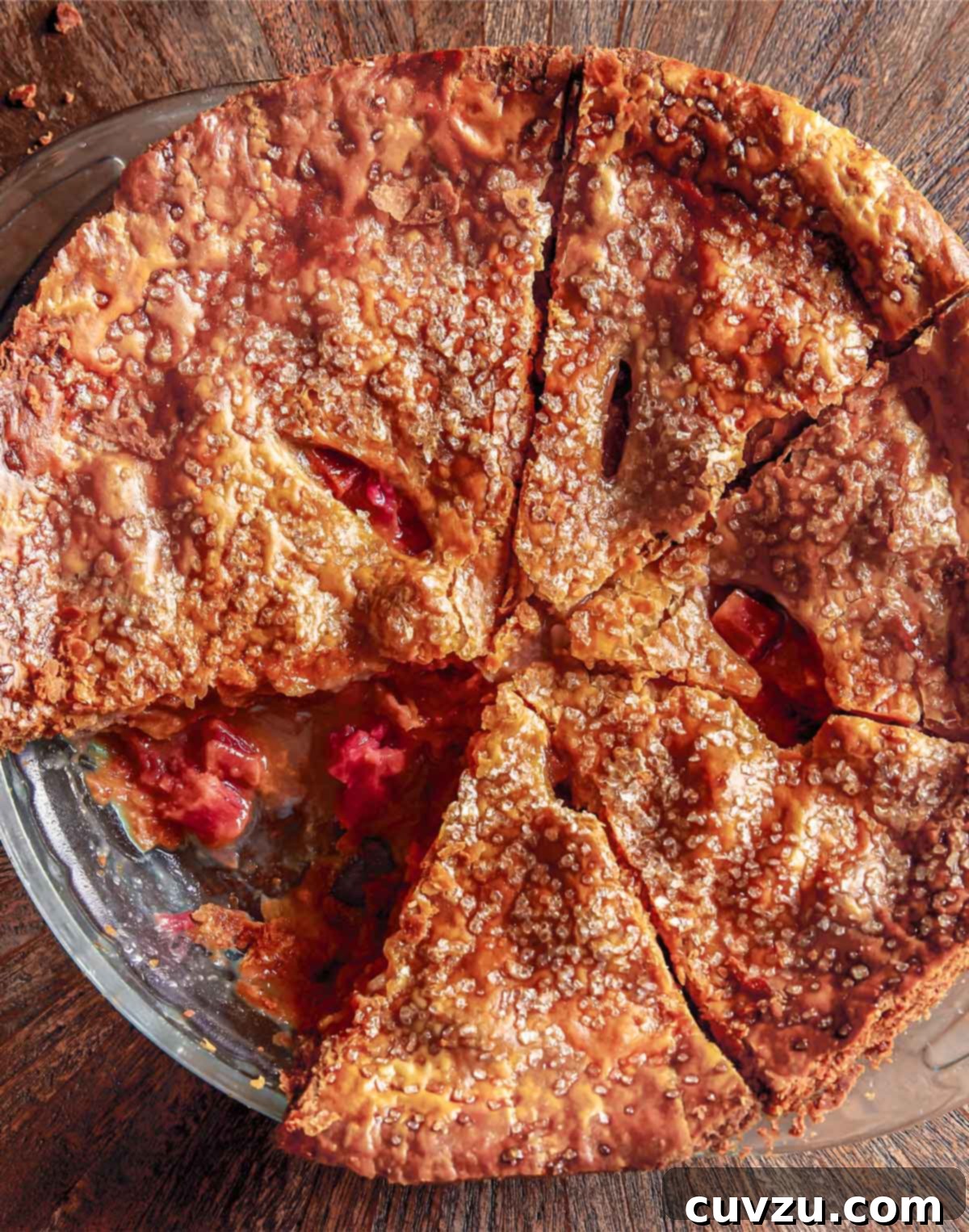 A rhubarb brown sugar pie cut into 7 wedges with one slice missing.