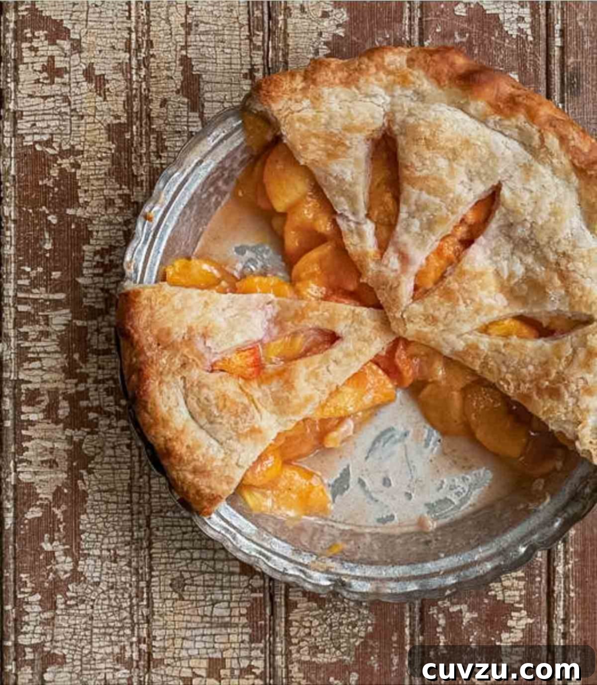 A baked fresh peach pie with three slices missing.