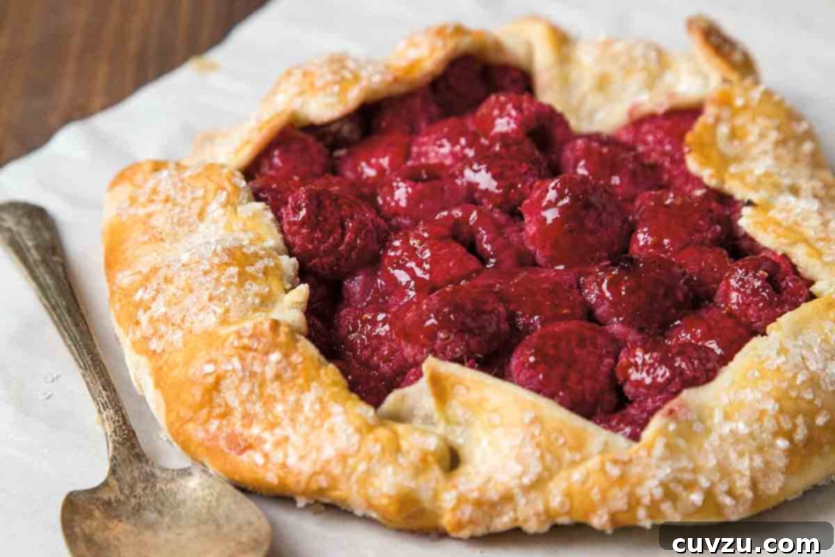 A raspberry crostata--a rustic tart with the crust folded over a filling of raspberries--on a sheet of parchment.