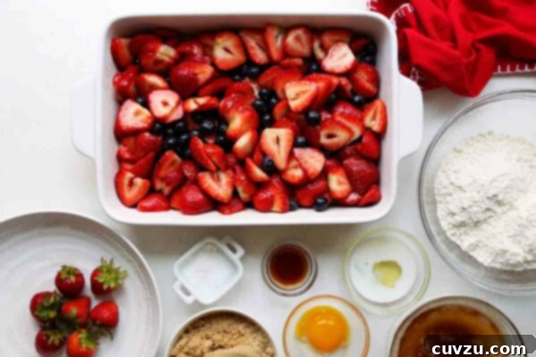 Sweet Summer Strawberry Blueberry Cobbler 4 A baking dish filled with fresh blueberries and sliced strawberries, gently tossed with a sugar and cornstarch mixture, ready to macerate for Joy the Baker's Strawberry-Blueberry Cobbler.