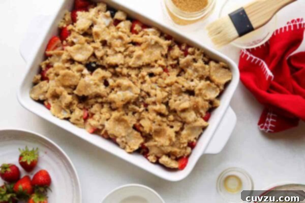 Sweet Summer Strawberry Blueberry Cobbler 6 Irregularly shaped dough coins arranged over a bed of macerated strawberries and blueberries in a baking dish, forming the topping for Joy the Baker's Strawberry-Blueberry Cobbler.