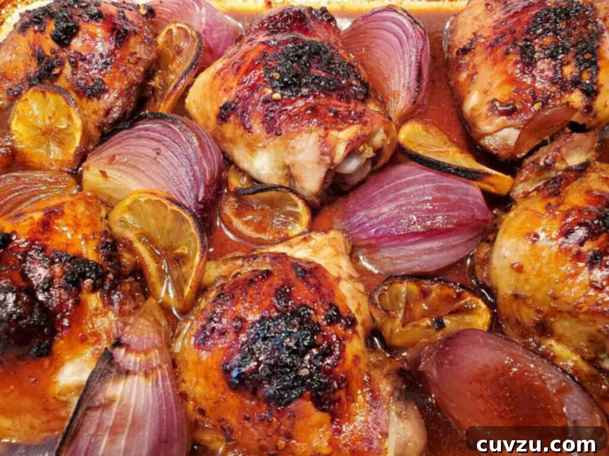 Zesty Lemon Ginger Chicken 8 Roasted lemon ginger chicken on a baking sheet, featuring crispy skin and sweet onions, prepared by Robin Currie.