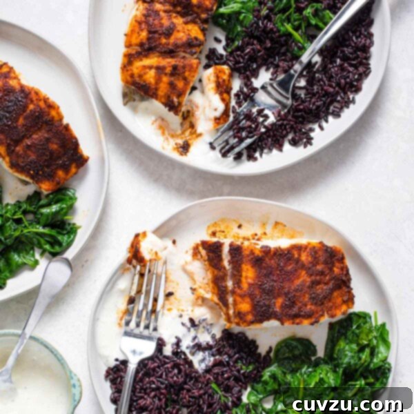 Three white plates with blackened red snapper, black rice, yogurt sauce, and sauteed spinach.