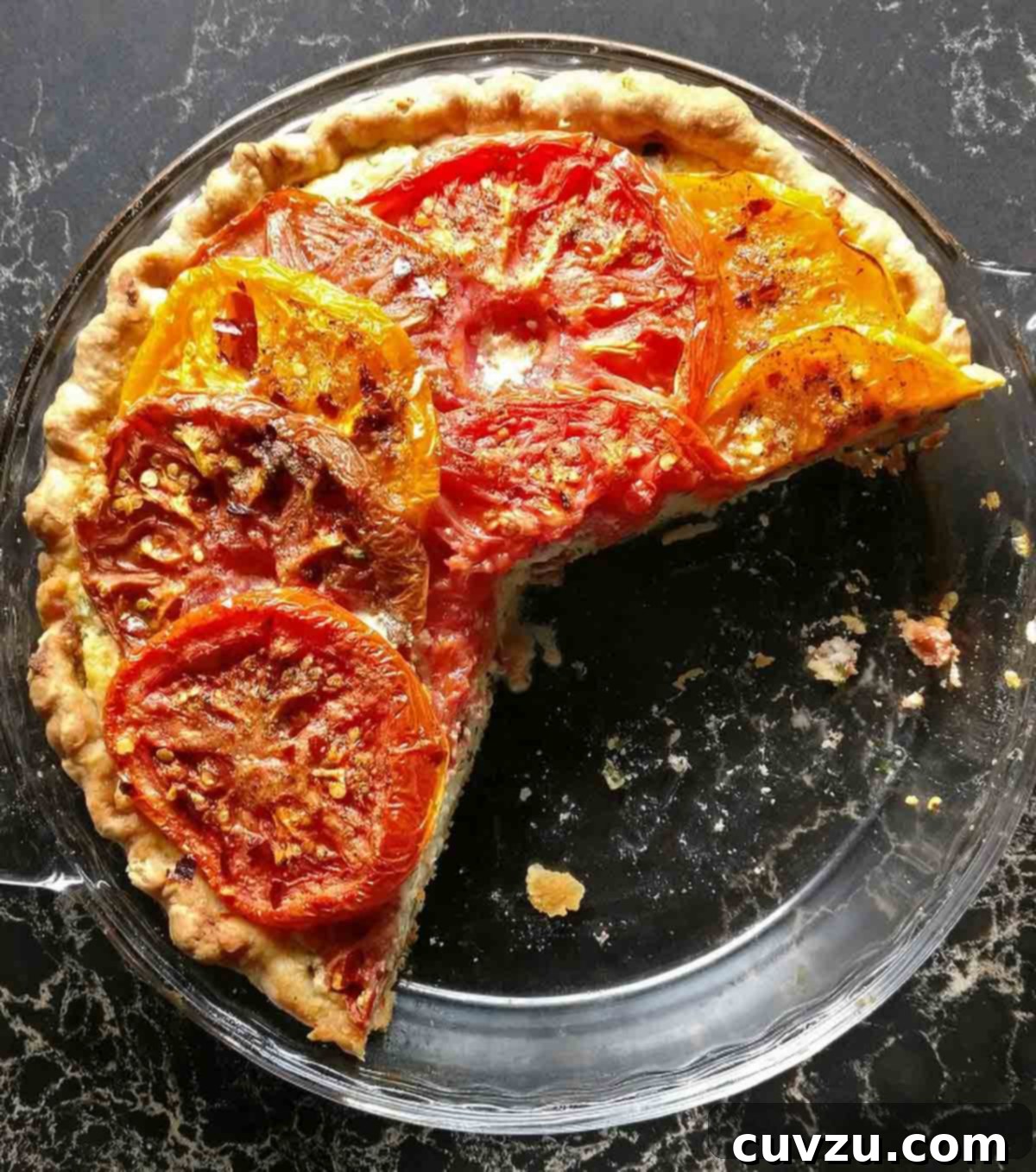 Savory Tomato Ricotta Tart 6 A glass pie plate with 2 thirds of a tomato cheese pie remaining, on a marble countertop.