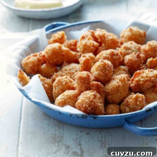 Crispy Cauliflower Poppers 4 A blue skillet with paper towel and a pile of breaded, deep-fried cauliflower. A bowl of dip in the background.