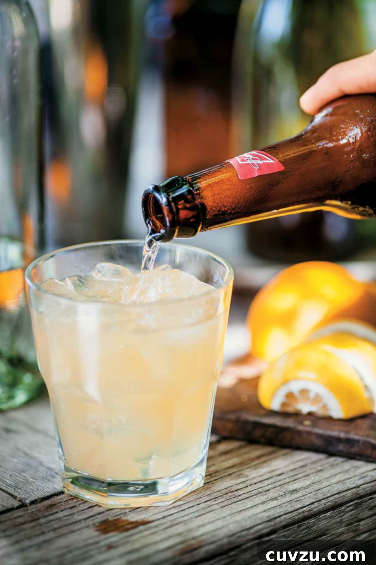 Beer from a Budweiser bottle being poured into a glass of mean shandy.