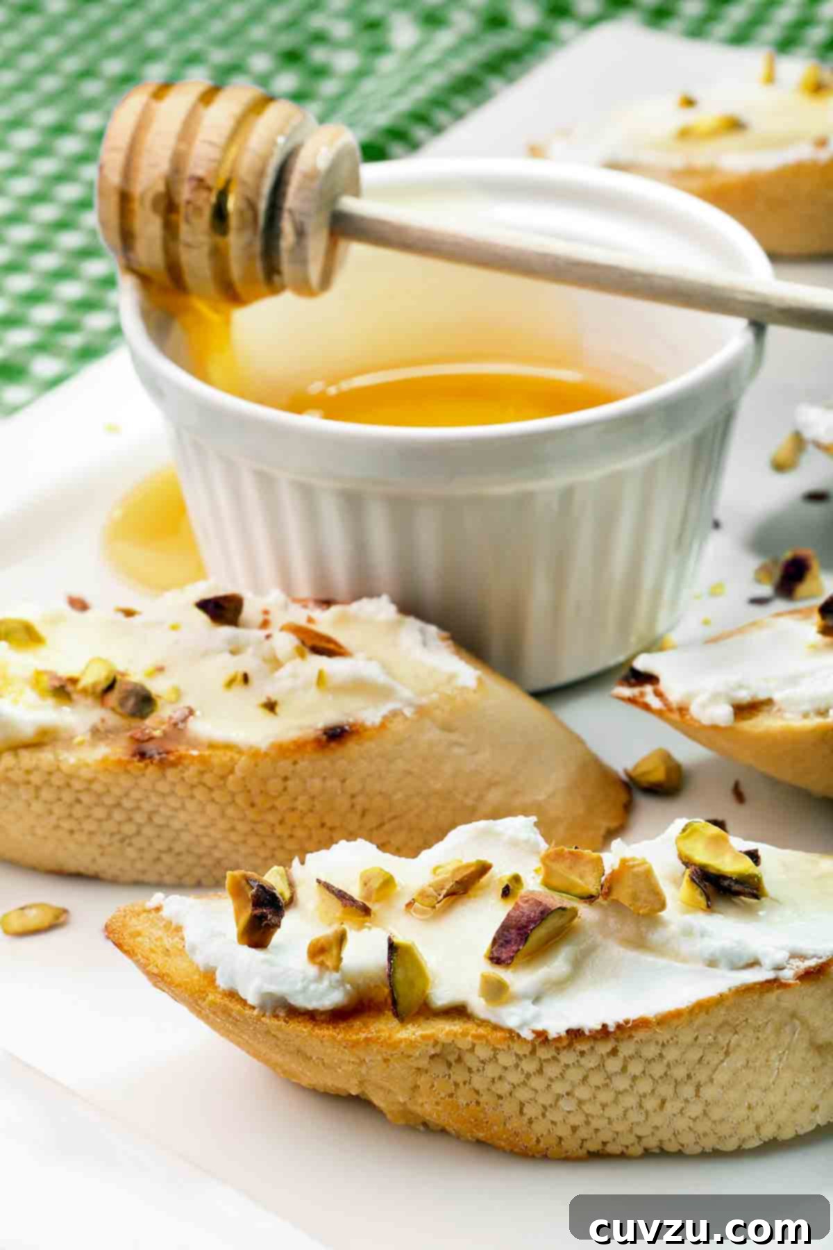 Rosh Hashanah Feasts: 11 Must-Try Recipes 6 Toasted rounds of baguette topped with goat cheese and chopped pistachios with a dish of honey in the background.