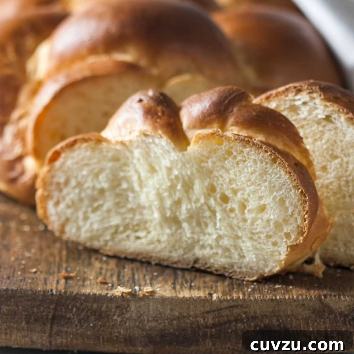 Rosh Hashanah Feasts: 11 Must-Try Recipes 9 A partially sliced loaf of challah on a wooden cutting board.