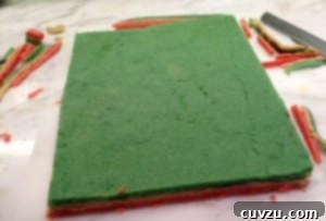 Trimming the uneven edges of the stacked rainbow cookie cake layers.