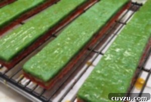 Brushing the warm apricot glaze on the strips of compressed rainbow cookie cakes.