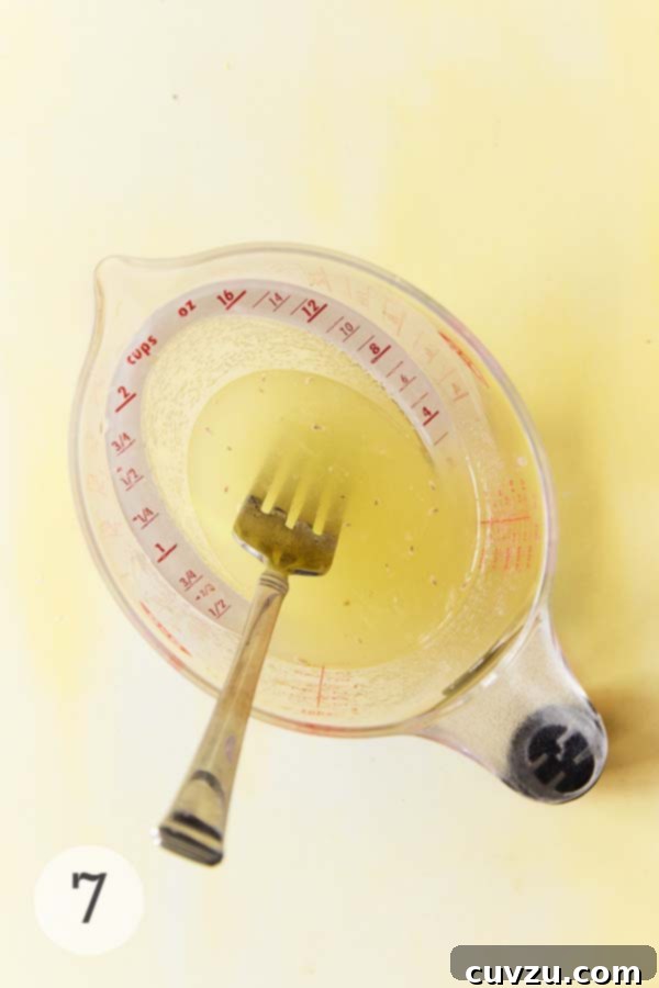 Zesty Lemon Loaf 13 Glass measuring cup filled with lemon syrup and a fork resting inside.