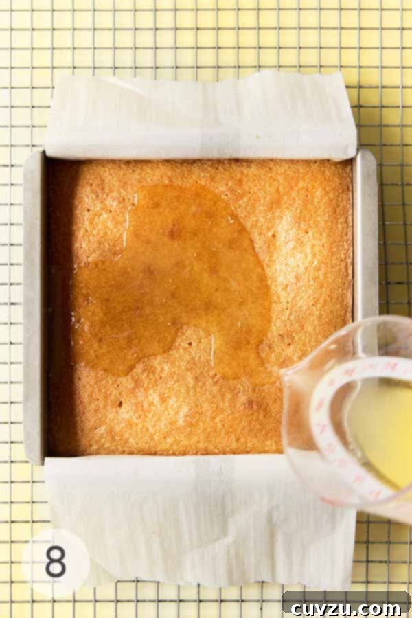 Zesty Lemon Loaf 14 Baked lemon drizzle cake in pan being soaked with lemon syrup.
