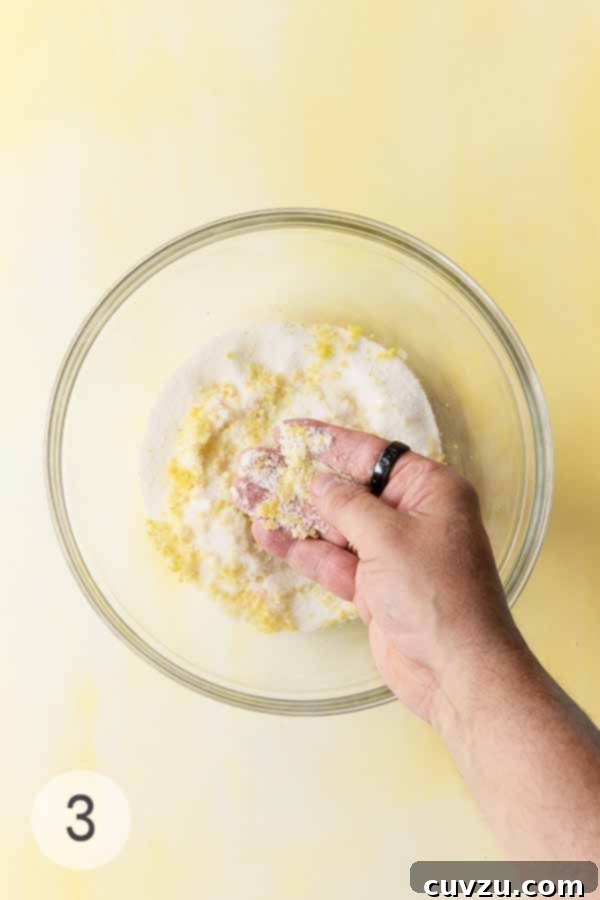 Zesty Lemon Loaf 9 Hand rubbing fresh lemon zest into a bowl of sugar for extra citrus flavor.